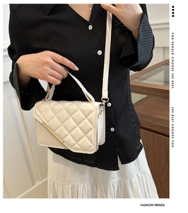 Detail of cream quilted crossbody bag with gold metal trim worn by a model