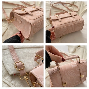 Détail de la texture marbre rose, ferrures dorées et bandoulière de ce sac à main femme