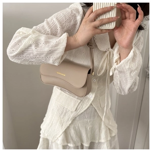 Close-up of a beige faux leather crossbody bag with golden Fashion & Bags text detail
