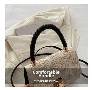 Detail of embroidered straw bag with black woven handle and gold twist lock closure