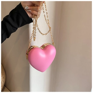 Detail of pink heart-shaped hard shell crossbody bag with gold chain and metal frame
