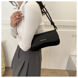 Detail of black faux leather shoulder bag with gold lettering and knotted strap