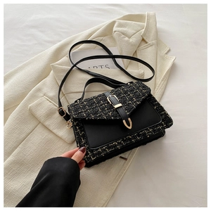 Détail du sac bandoulière en tweed et cuir noir avec boucle dorée sur blazer beige