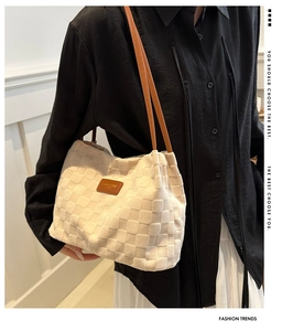 Detail of white woven checkerboard tote bag with brown leather strap on model