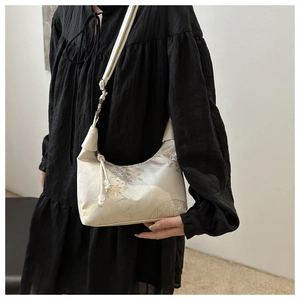 Detailed embroidery of purple flowers and bamboo on a white satin crescent crossbody bag