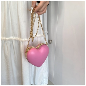 Detail of pink heart-shaped hard shell bag with gold metal trim and fine chain strap