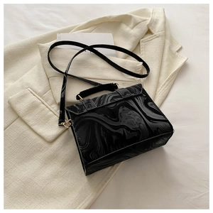 Détail macro du sac à main à motif marbre noir avec finition brillante et fermoir doré
