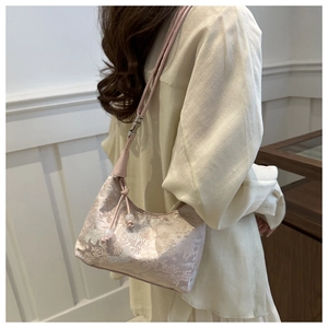 Detail of floral jacquard fabric on pink bucket bag with pearl zipper pendant