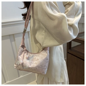 Detail of pink embroidered silk bucket bag with pearl charm and adjustable strap