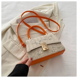 Detail of woven straw handbag with floral embroidery and orange leather strap