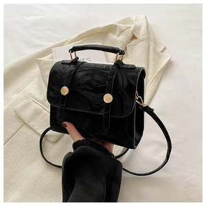 Détail du sac noir en cuir marbré avec boucles dorées et poignée métallique
