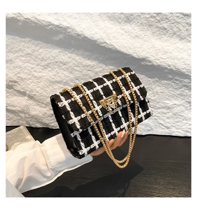 Detail view of black and white plaid tweed fabric with gold chain strap and metal buckle