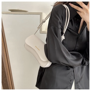 Detail of cream minimalist underarm bag with woven knot strap on model's shoulder