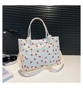 Detail of white corduroy tote bag with strawberry print and adjustable shoulder strap