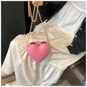 Detail of pink heart-shaped hard shell clutch with gold chain strap for women