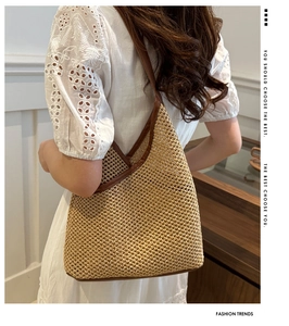 Detail of woven straw bucket bag with dark brown leather trim and shoulder strap