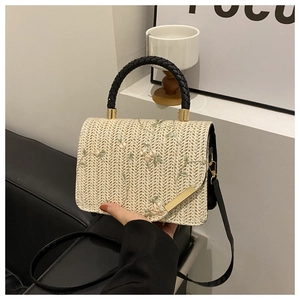 Detailed embroidery of pink flowers and green vines on a natural straw handbag