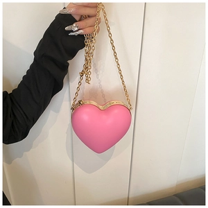 Detail of a bright pink heart-shaped hard shell clutch bag with gold chain and metal clasp