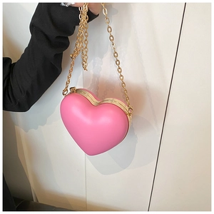 Detailed view of a pink heart-shaped hard shell crossbody bag with a gold chain strap