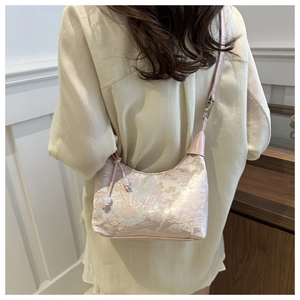 Detail of embroidered floral patterns on a pink brocade crescent shoulder bag