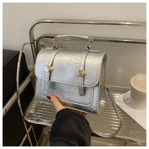 Détail du sac à main argenté de style ballet avec boucle dorée et texture plissée