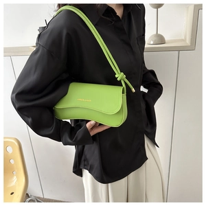 Detail of neon green shoulder bag with wavy flap and knot strap on a black shirt model