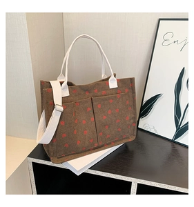 Detail of brown corduroy tote bag with strawberry print and white woven handles