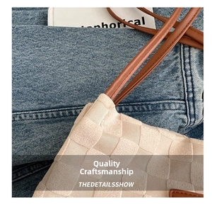 Close-up of cream woven tote bag featuring grid texture and brown leather strap detail