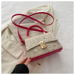 Detail of floral embroidery on beige fabric with vibrant fuchsia leather handles and gold lock