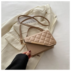 Detail of khaki quilted leather handbag with gold metal bar on an ivory blazer background