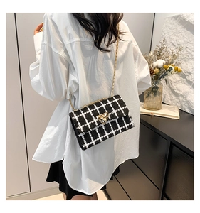 Close-up of black and white checkered tweed bag with gold chain strap and lock detail