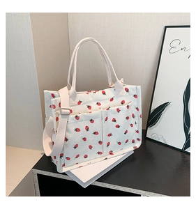 Detailed close-up of corduroy strawberry tote bag featuring front pockets and crossbody strap