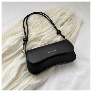 Detail of black leather bag showing the gold fashion logo and knotted strap accent