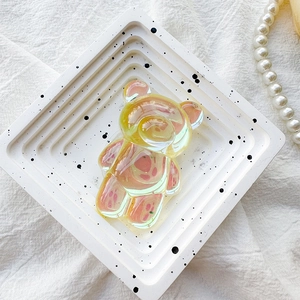 Close-up of translucent yellow bear phone grip with iridescent laser finish on white tray