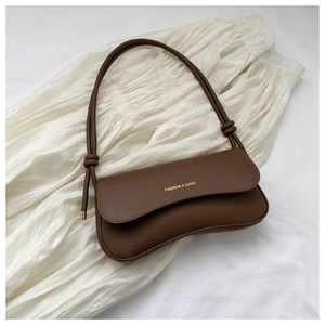 Detail of a brown half-moon shoulder bag with matte leather texture and knot strap