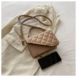Detail of khaki quilted handbag with gold metal trim on elegant fabric background