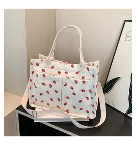 Detail of strawberry corduroy tote bag showing front pockets and adjustable strap