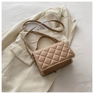Detail of beige quilted crossbody bag showing leather texture and gold hardware on a suit