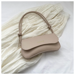 Close-up of beige faux leather shoulder bag with knotted strap and gold foil logo text