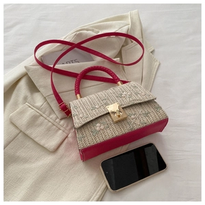 Detail of retro straw woven bag with floral embroidery, pink leather trim and metal lock