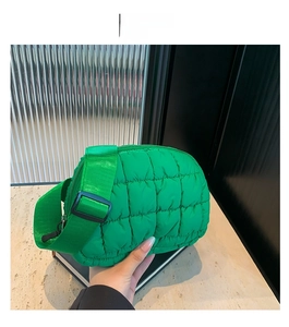 Détail d'un sac bandoulière matelassé vert avec bandoulière réglable tenu à la main