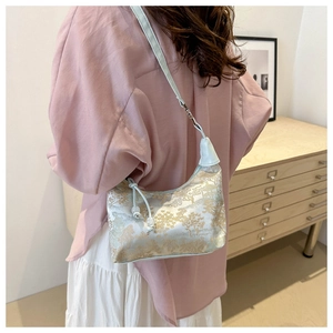 Detail of blue silk hobo bag with gold landscape embroidery and beaded strap accents