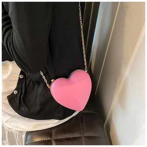 Detail of pink heart-shaped crossbody bag with gold metal frame and chain strap