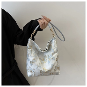 Detail of embroidered butterfly pattern on ivory jacquard fabric with blue handles