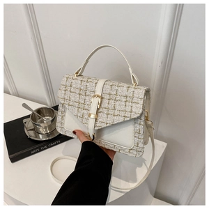 Détail d'un sac à main en tweed blanc avec boucle dorée et bandoulière amovible chic
