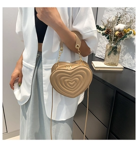 Detailansicht der beigen herzförmigen Stepptasche mit Goldkette und Doppelreißverschluss
