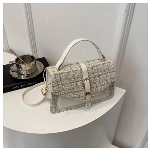 Détail de la texture en tweed crème et de la bordure en cuir blanc sur le sac à rabat