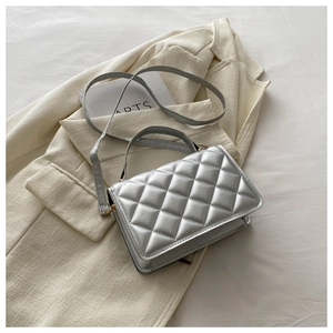 Detail of silver quilted crossbody bag with top handle and adjustable shoulder strap