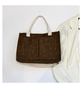 Detail of strawberry corduroy tote bag showing front pockets and white woven handles