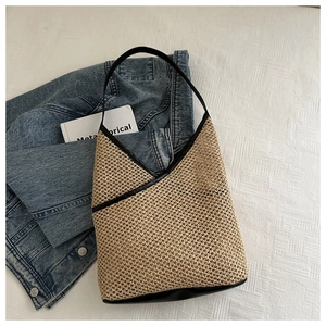 Close-up of woven straw shoulder bag with black leather trim and textured straw detail